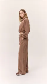 Buzo cropped de cuello alto con cordón regulable, mangas largas con puños elásticos y cintura ajustable con cordón. Presenta un diseño moderno y versátil con acabado suave.