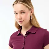 Remera polo de manga corta en tejido de punto canalé color bordó, con cuello camisero y cierre frontal de botones.