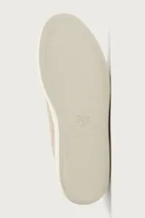 Zapatilla de piel con acabado en serraje de color gris, diseño de cordones ocultos y suela de goma en contraste de color blanco.