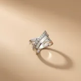 Anillo de plata 925 con diseño cruzado, compuesto por bandas lisas y una banda central engastada con pequeñas circonias brillantes.