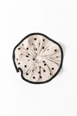 Gomita scrunchie de tela color crema con estampado de lunares negros y borde de cinta negra.