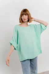 Blusa de lino color verde oliva, de corte amplio y relajado, con escote redondo y mangas 3/4 remangadas.