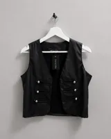 Chaleco de cuero sintético color negro, con escote en V y detalles de trabillas con botones metálicos plateados en el frente. Marca Genora.