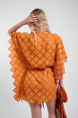 Vestido camisero oversize de color naranja en tela calada con diseño geométrico, cuello tipo solapa, mangas anchas y ruedo con terminación en picos. Cuenta con lazo ajustable en la cintura.