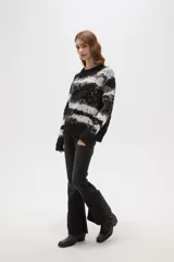 Sweater de tejido jacquard con diseño de rayas irregulares en tonos negro, blanco y gris. Presenta cuello redondo a la base, mangas largas y un corte holgado.