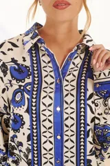 Camisa de manga larga con cuello clásico y cierre de botones. Estampado con motivos florales y geométricos en tonos crudo, azul y negro.
