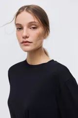 Top de punto color negro con detalle de nudo girado en la cintura, escote redondo, hombros caídos y mangas largas amplias.
