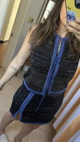 Conjunto de falda y top tejido calado en color negro con lurex plateado y detalles en azul. La falda es mini con tajo lateral. El top es sin mangas y con escote en V con cordones ajustables.