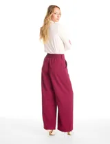Pantalón tipo palazzo de corte ancho y fluido, confeccionado en tejido sastrero. Presenta tiro alto con doble abotonadura frontal, pinzas decorativas y cintura elástica en la parte posterior. Incluye bolsillos laterales funcionales.