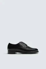 Zapato de vestir estilo Derby, color negro, fabricado en piel con horma redonda y suela con ligero tacón.