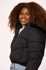 Campera bomber de nylon color rosado, con diseño acolchado, cierre frontal con cremallera y botones a presión, y capucha con borde de piel sintética al tono.