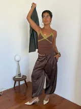 Pantalón de corte holgado y tiro alto, confeccionado en tela satinada color marrón oscuro. Presenta cintura elástica con cordón ajustable y diseño amplio en las piernas.