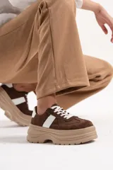 Championes de plataforma con diseño chunky, confeccionados en material símil gamuza color marrón chocolate con detalles en blanco en los laterales y cordones al tono.