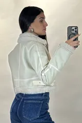 Campera tipo gamulán de cuero sintético negro, con interior y detalles de cuello y puños en corderito blanco. Presenta cierre frontal, cierres en los puños y correas ajustables en la cintura.