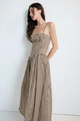 Vestido midi de popelín con estampado de rayas verticales. Presenta escote recto con detalle de pliegues, tirantes finos y falda con corte evasé. Incluye cierre lateral con cremallera oculta.