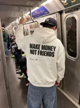 Hoodie color crema con capucha, de corte holgado y diseño estampado en la espalda con la frase 'MAKE MONEY NOT FRIENDS' en letras negras y una firma debajo.