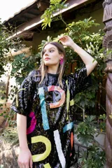 Vestido corto negro de lentejuelas con diseño de letras multicolores.