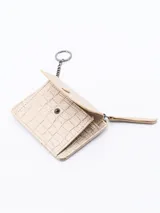 Billetera plateada con textura símil piel de cocodrilo, cierre de cremallera superior y solapa frontal con botón a presión.