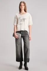 Remera color crudo de calce boxy, confeccionada en jersey de algodón con elastano. Tiene cuello redondo en rib a tono y manga corta. Incluye estampa en delantero con la frase 'My favorite outfit is love' combinada con cristales hotfix a tono.