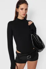 Body negro de algodón con lycra, de corte ajustado, manga larga con detalle de mitón en los puños y cuello media polera. Cierre con botones a presión en la entrepierna.