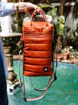 Bolso matero negro de cuero sintético con diseño capitoneado, correa larga regulable y doble asa corta.