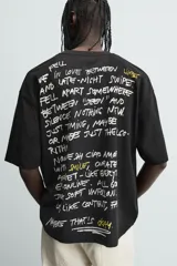 Camiseta negra de corte boxy fit, cuello redondo y manga corta, con estampado frontal en blanco y amarillo que dice "Social Media & Ciao Amore".