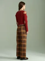 Saco de punto acanalado color bordó con detalles en color crudo en el cuello, plaqueta de botones y ruedo. Presenta aberturas en los hombros y cierre frontal con botones pequeños.