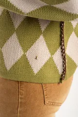 Sweater de tejido de punto con diseño de rombos en tonos verde oliva y beige, cuello redondo y mangas largas.