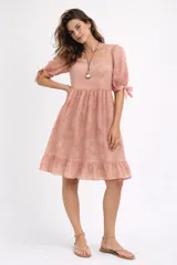 Vestido a la rodilla blanco y rosado, con bordado floral en el escote, mangas 3/4 con lazo y falda fruncida.