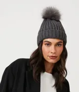 Gorro de punto acanalado en color blanco, con diseño de bajo plegado y pompón superior a tono.