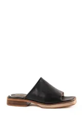 Zueco de cuero negro, con pala ancha, punta cuadrada y suela de madera con tacón bajo.