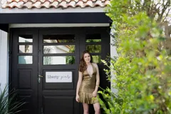 Vestido corto negro con escote en V profundo, estilo halter con tiras para atar al cuello. Presenta un diseño ajustado en el busto con tiras ajustables bajo el mismo que se cruzan y anudan en la espalda, y falda con volado en el ruedo con detalle de encaje.