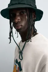 Camiseta de manga corta y cuello redondo, color blanco hueso, con un estampado abstracto multicolor en el pecho que incluye texto en la parte inferior.