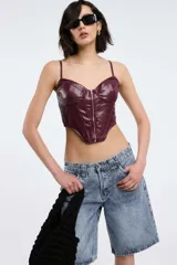Bustier color borgoña de cuero sintético con tirantes finos y cierre frontal con cremallera.