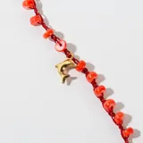 Collar corto con cadena de hilo rojo con cuentas de color coral y dijes colgantes de estrella de mar y pez en color dorado.