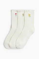 Pack de tres pares de medias de punto acanalado color blanco, con borde superior elástico y ribete sobrehilado. Cada par presenta un delicado bordado floral diferente.