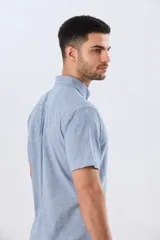 Camisa de manga corta confeccionada en mezcla de lino y algodón, con estampado de cuadros pequeños en tonos azules. Presenta cuello camisero con botones, cierre frontal abotonado, bolsillo aplicado en el pecho y dobladillo redondeado.