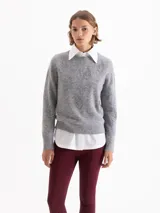 Sweater de tejido de punto gris con textura de pelo, cuello redondo y mangas largas. Presenta un bordado frontal de piedras brillantes con forma de flamas.