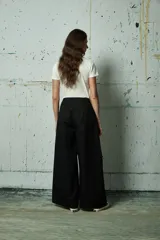 Pantalón de vestir negro de corte ancho y tiro alto, con pinzas frontales y cierre oculto.