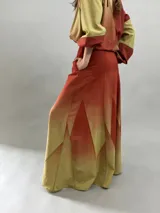 Falda larga de lana con diseño de paneles geométricos y efecto degradado que transiciona de verde esmeralda a tonos amarillentos. Presenta cintura alta, cierre invisible lateral y bolsillos ocultos.