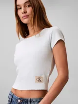 Remera Calvin Klein de manga corta y corte crop top, confeccionada en tejido de punto acanalado de algodón con elastano. Presenta cuello redondo y una pequeña etiqueta rectangular con el logo de la marca en el dobladillo inferior.