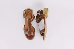 Sandalias de cuero color marrón con diseño de tiras en forma de T y hebilla lateral.