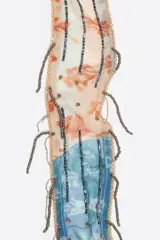 Pañuelo rectangular con estampado tipo patchwork en tonos celeste, naranja y blanco, con flecos de cuentas metálicas.