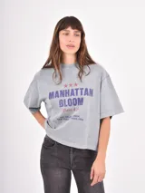 Remera de corte holgado y diseño oversize, color azul piedra con efecto lavado. Presenta un estampado gráfico frontal con tipografía y un pequeño dibujo de una rosa.