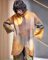 Tapado de lana merino afieltrada color ocre con teñido artesanal tie dye en forma de luna, cierre cruzado asimétrico con broches, cuello alto y bolsillos laterales.