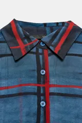 Camisa de manga larga con cuello solapa y cierre frontal con botones. Presenta un diseño de cuadros en tonos azules y rojos sobre un tejido semitransparente.
