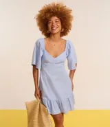 Vestido corto evasé color celeste, con escote en V, mangas cortas amplias, recorte cutout en los laterales de la cintura y volado en el bajo.