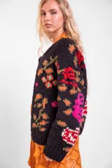 Cardigan de lana merino tejido y bordado a mano de calce holgado con cuello a la base, mangas largas y cierre frontal de botones. Presenta un diseño artesanal con bordados coloridos en las mangas y el cuerpo.