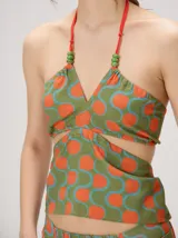 Top halter estampado en tonos rojo y beige, con tirantes finos ajustables al cuello y detalle de cuentas.
