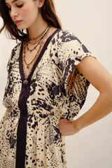 Vestido largo beige con estampado animal print oscuro y detalles en color negro, escote en V y mangas cortas holgadas.